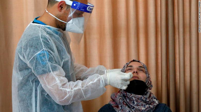 عامل صحي فلسطيني يجري فحص الـ PCR لسيدة في الضفة الغربية، جنوب غرب الخليل ، 8 يناير، 2021. Photo Credit: CNN